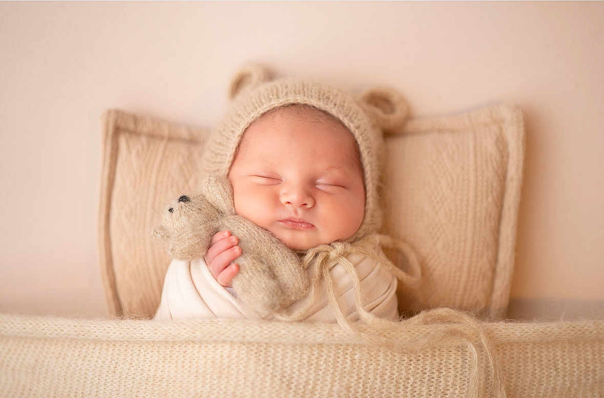 Sohan a rejoint le concours — aidez-le/la à gagner de superbes lots ! baby, sleeping, knit_hat, teddy_bear, blanket, pillow, cozy, soft_texture, infant, cute, wrapped, peaceful, child, indoors, portrait, warm_colors, newborn, hand, face, resting