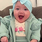 Romah Mae joined the competition — help win amazing prizes! baby, child, headband, bow, happy, smiling, clothing, jacket, pants, sitting, indoor, person, cute, face, hand, apparel, joyful, infant, seat, expression