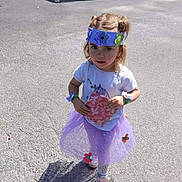 Annaëlle participe au concours pour gagner de l'argent avec cette photo : child, girl, tutu, purple, flower_crown, pigtails, sneakers, outdoor, sunlight, playful, paper, curious, costume, pavement, shadow, casual_clothing, decorations, standing, person, daylight