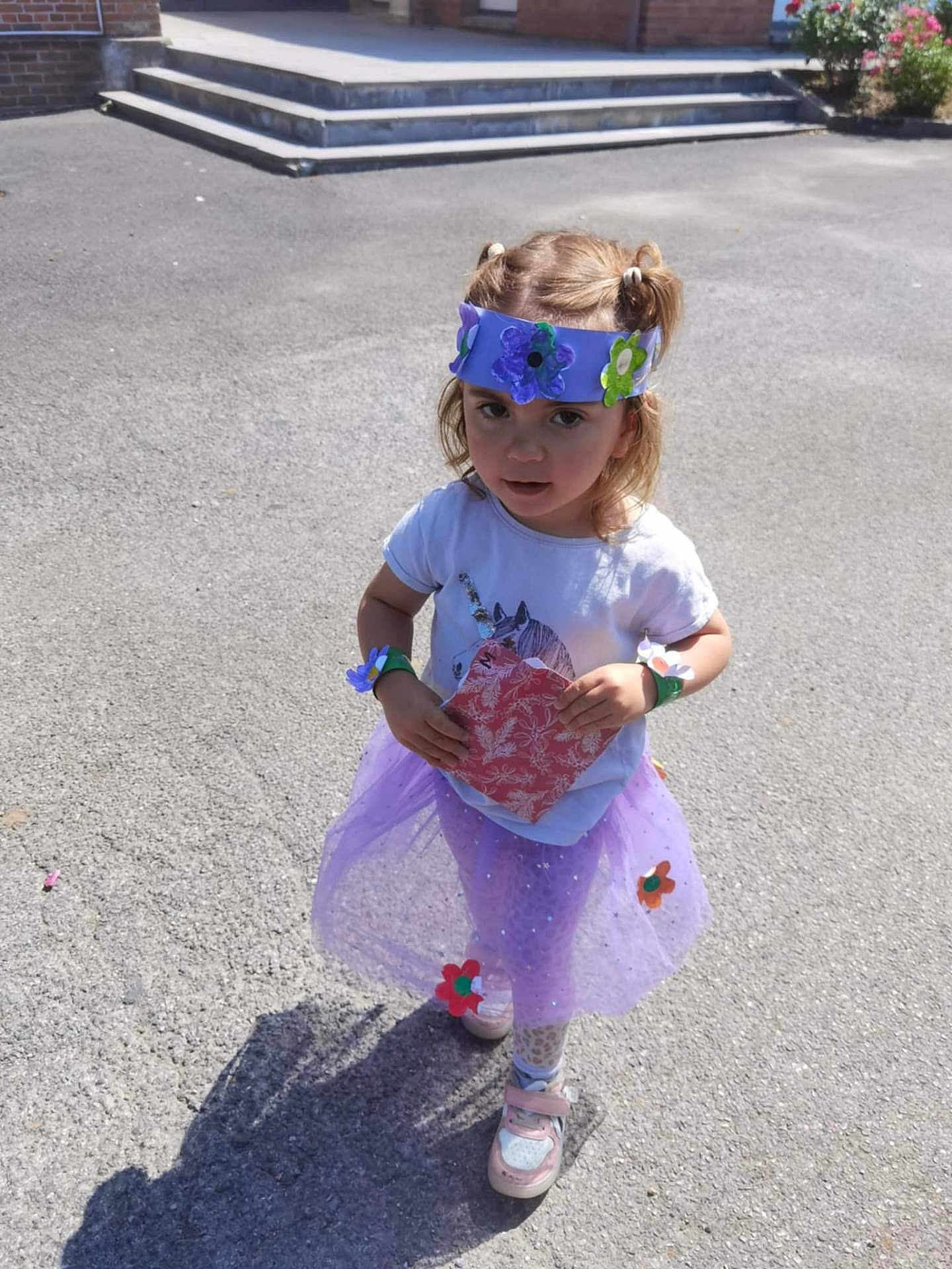 Annaëlle participe au concours pour gagner de l'argent avec cette photo : child, girl, tutu, purple, flower_crown, pigtails, sneakers, outdoor, sunlight, playful, paper, curious, costume, pavement, shadow, casual_clothing, decorations, standing, person, daylight