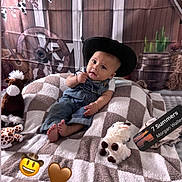 Julian joined the competition — help win amazing prizes! baby, cowboy_hat, plush_toy, blanket, denim_overalls, cute, indoors, child, western_theme, cowboy, hat, soft_toy, checkered_blanket, decor, background, baby_boy, face, portrait, sitting, playful
