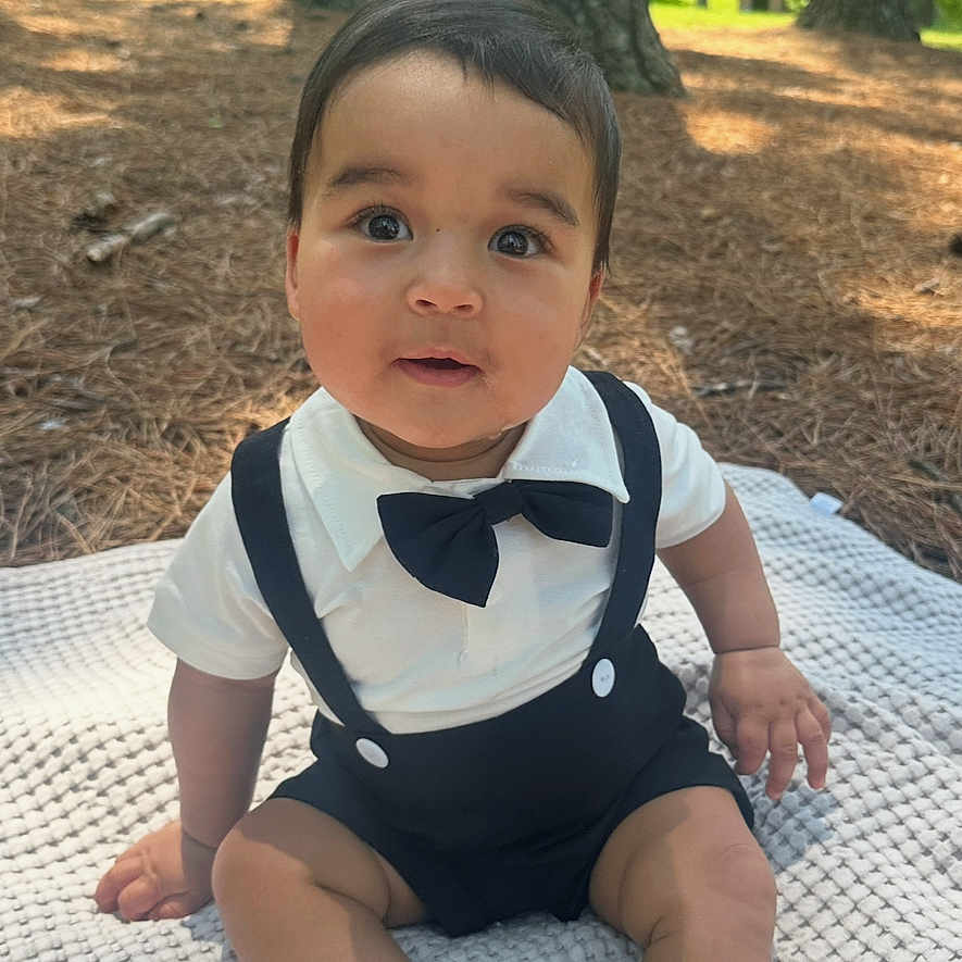 Bryson is registered to the contest to win money with this photo: baby, child, outdoor, nature, trees, blanket, bow_tie, suspenders, cute, infant, grass, sunlight, portrait, sitting, forest, young, person, happy, casual, daylight