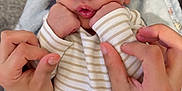 Raymon is registered to the contest to win money with this photo: baby, infant, hands, blanket, striped_clothing, sleeping, cute, peaceful, soft, newborn, person, skin, fingers, puckered_lips, closeup, indoors, tender, cozy, resting, child
