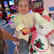 Elif participe au concours pour gagner de l'argent avec cette photo : child, girl, pigtails, smiling, carousel, horse, arcade, ride, toy, indoor, fun, amusement, happy, playful, colorful, clothing, jeans, white, lights, entertainment