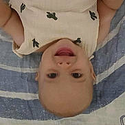 Anthony is registered to the contest to win money with this photo: baby, smiling, infant, child, blanket, striped_blanket, clothing, happy, face, head, lying_down, arm, patterned_clothing, indoors, cute, skin, young_child, portrait, expression, casual