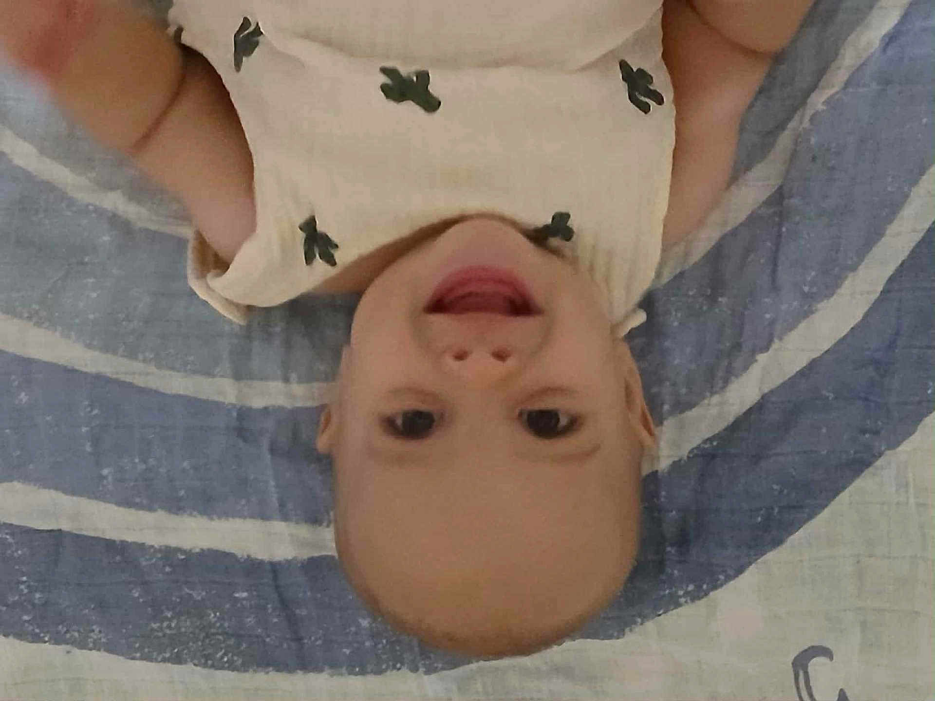 Anthony is registered to the contest to win money with this photo: baby, smiling, infant, child, blanket, striped_blanket, clothing, happy, face, head, lying_down, arm, patterned_clothing, indoors, cute, skin, young_child, portrait, expression, casual