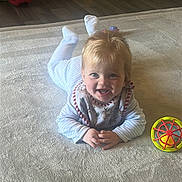 George joined the competition — help win amazing prizes! baby, child, toddler, smiling, indoor, carpet, toy, colorful_toy, floor, light_hair, happy, face, clothing, bib, playtime, furniture, chair, wooden_floor, home, cute