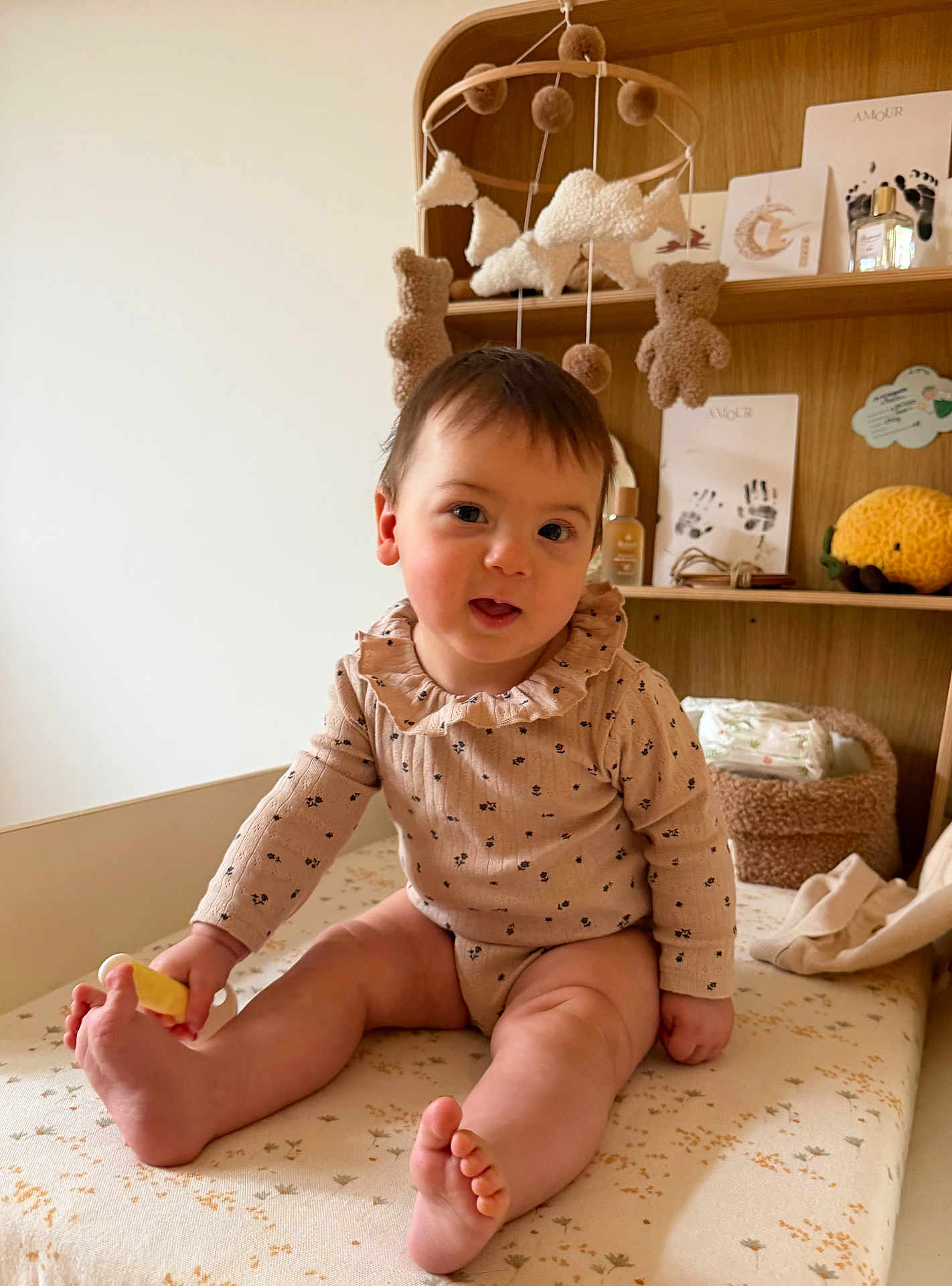 Malou a rejoint le concours — aidez-le/la à gagner de superbes lots ! baby, infant, child, nursery, mobile, stuffed_toys, teddy_bear, changing_table, bookshelf, wooden_shelf, onesie, sitting, toes, diaper, toy, portrait, indoor, cozy, smile, handprint_card