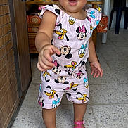 Inaya participe au concours pour gagner de l'argent avec cette photo : child, colorful_clothing, curly_hair, disney, donald_duck, indoor, mickey_mouse, minnie_mouse, person, pink_sandals, playful, pluto, reaching, shorts, smiling, standing, tile_floor, toddler, water_bottles, wooden_furniture