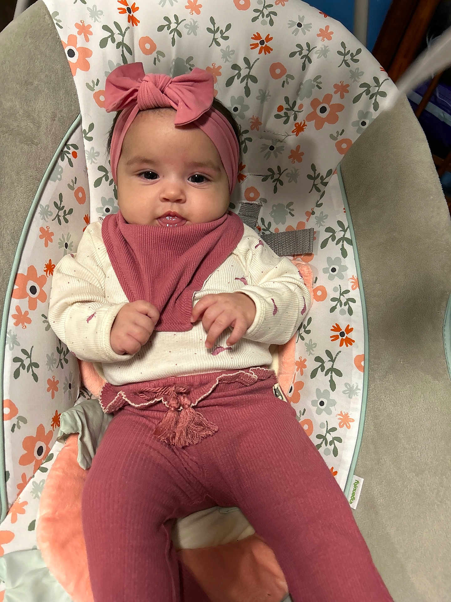Sofia is registered to the contest to win money with this photo: baby, infant, headband, bow, bib, onesie, leggings, bouncer_seat, floral_pattern, drool, hands, cheeks, eyes, smile, cushion, pastel_colors, clothing, portrait, indoor, safety_strap