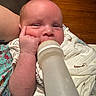 Messiah is registered to the contest to win money with this photo: baby, bottle, feeding, infant, blanket, hand, face, skin, expression, closeup, indoor, person, young, cute, milk, sleepwear, wood, resting, comfort, newborn