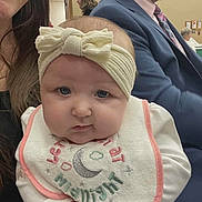 Ariel joined the competition — help win amazing prizes! baby, headband, bib, woman, man, suit, tie, indoor, portrait, smile, chubby_cheeks, hand, people, clothing, face, expression, background, seated, adult, casual