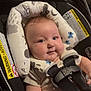 Ariel is registered to the contest to win money with this photo: baby, car_seat, child, infant, harness, seatbelt, cushion, patterned, soft, smiling, chubby_cheeks, cute, indoor, person, head, face, clothing, straps, sitting, closeup