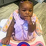 Hunter Elyza joined the competition — help win amazing prizes! baby, child, infant, portrait, sitting, high_chair, activity_walker, toy, colorful, purple_outfit, hair_clips, curious, finger_in_mouth, indoors, tile_floor, home, smiling, dark_skin, headshot, playtime
