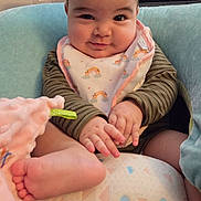 Violet is registered to the contest to win money with this photo: baby, infant, smile, face, foot, hand, bib, clothing, cushion, blanket, indoor, cute, happy, child, person, soft, striped, playful, skin, comfort