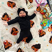Enora participe au concours pour gagner de l'argent avec cette photo : baby, infant, black_clothing, headband, blanket, moana, toy_giraffe, soft_toys, activity_book, smiling, happy, lying_down, floor, carpet, indoor, child, cute, playtime, colorful, cozy