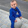 child, boy, blue_suit, bow_tie, smiling, sidewalk, cobblestone, stone_ball, urban, street, cars, casual, playful, fashion, outdoor, concrete, pavement, young, portrait, happy