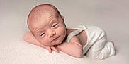 Kayden is registered to the contest to win money with this photo: baby, newborn, infant, sleepy, resting, white_clothing, knitwear, soft_texture, cream_blanket, portrait, cute, small_hands, head_support, neutral_background, skin_texture, lying_down, peaceful, indoors, closeup, person