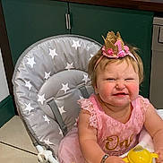 Violet is registered to the contest to win money with this photo: baby, birthday, high_chair, pink_dress, crown, smile, messy_face, sippy_cup, kitchen, tile_floor, celebration, child, one_year_old, happy, young_child, indoors, person, cup, fun, party