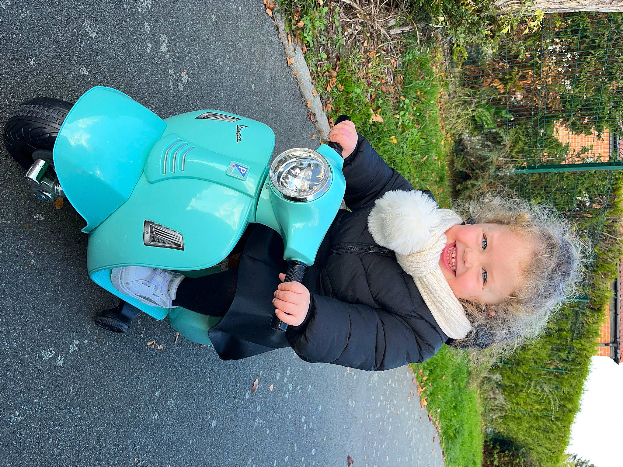 Talia participe au concours pour gagner de l'argent avec cette photo : asphalt, auto_part, automotive_design, automotive_lighting, automotive_tire, automotive_wheel_system, electric_blue, fender, grass, happy, headlamp, joy, motor_vehicle, person, plant, road_surface, scooter, smile, tire, toddler