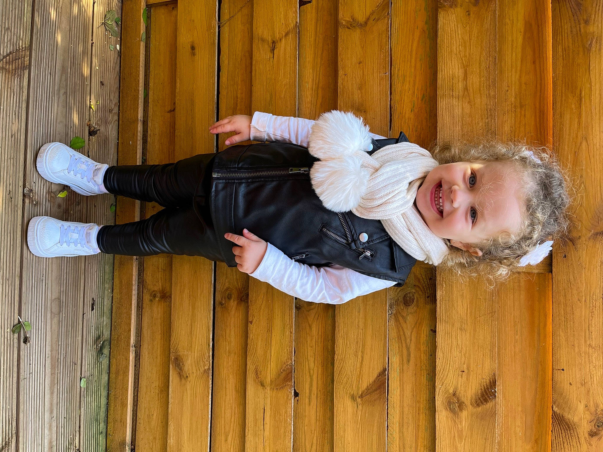Talia a rejoint le concours — aidez-le/la à gagner de superbes lots ! baby_toddler_clothing, child, fun, grass, happy, hardwood, joy, outdoor_shoe, people_in_nature, person, plank, portrait_photography, sitting, sleeve, smile, toddler, walking_shoe, wood, wood_stain