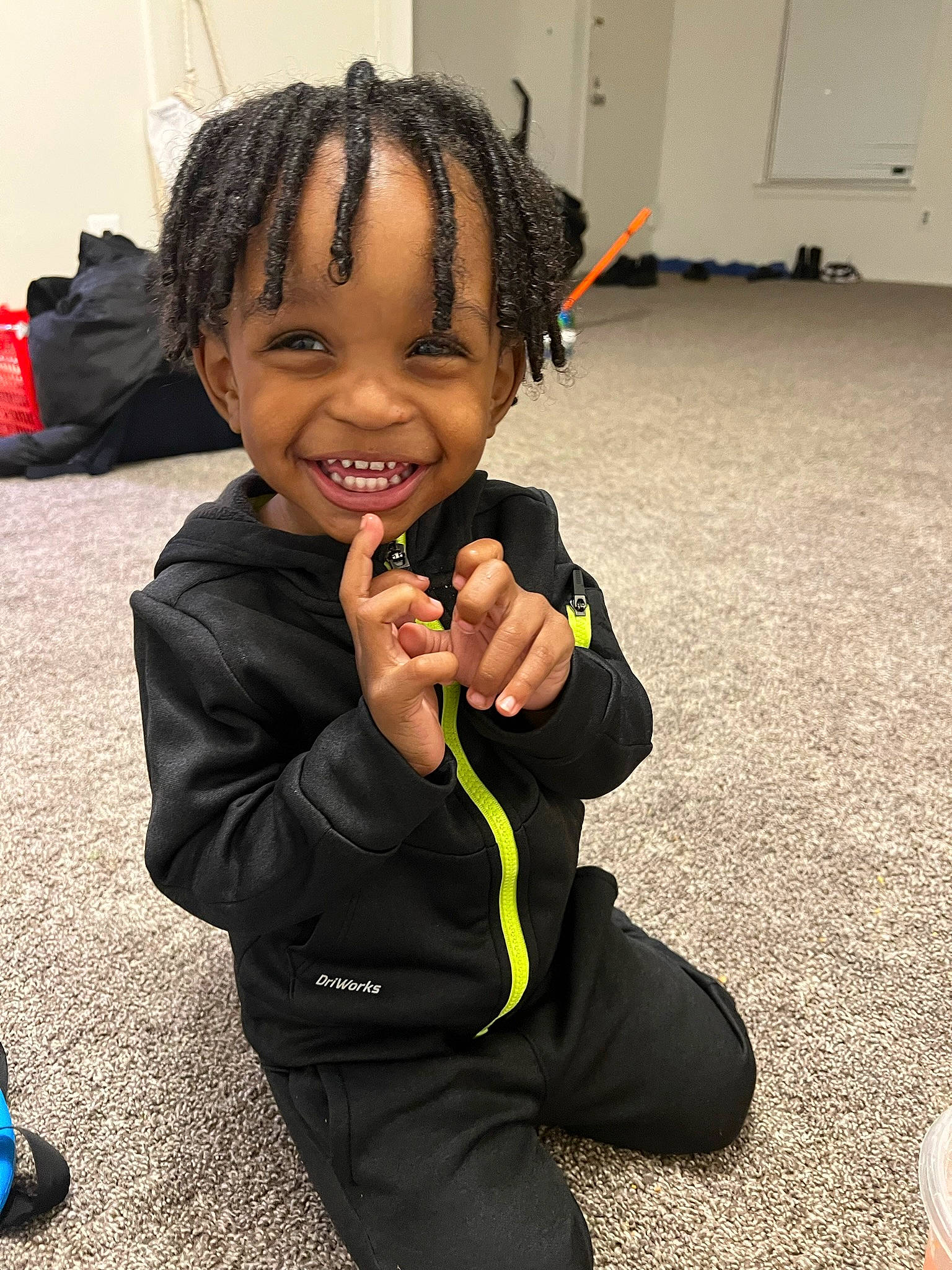 Demetrius is registered to the contest to win money with this photo: arm, audio_equipment, child, cornrows, dreadlocks, event, eye, flooring, formal_wear, fun, gesture, happy, head, joy, person, play, room, sitting, smile, thumb