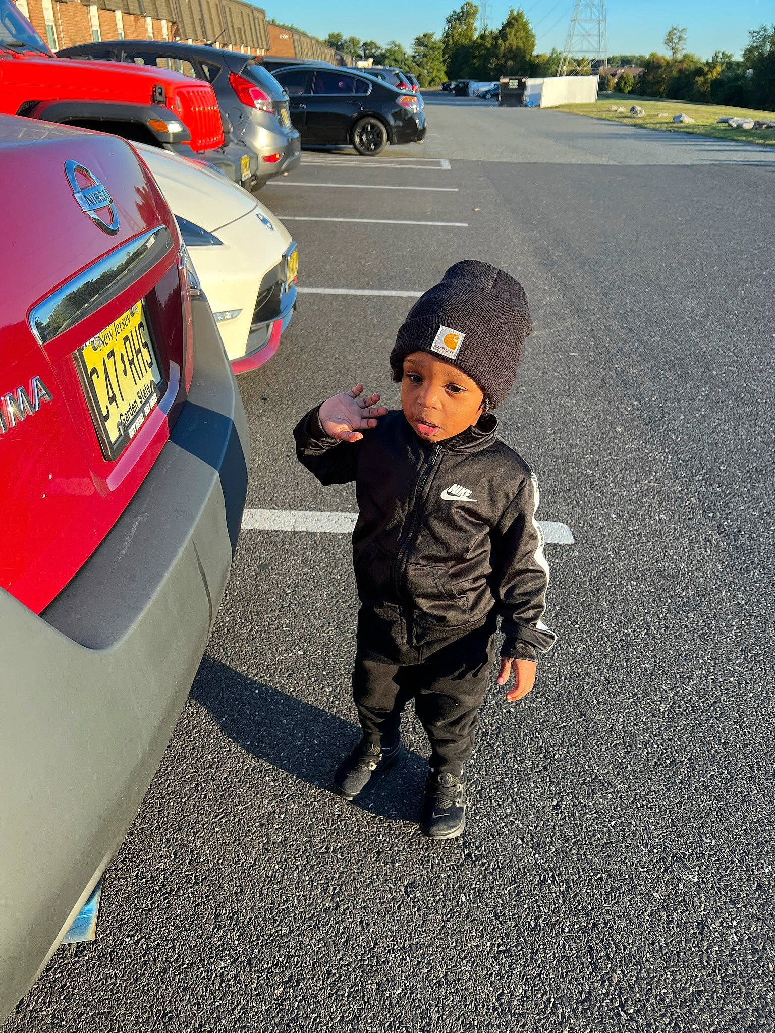 Demetrius is registered to the contest to win money with this photo: asphalt, automotive_design, automotive_exterior, automotive_lighting, automotive_tail_brake_light, automotive_tire, car, hat, headwear, land_vehicle, motor_vehicle, parking, person, road_surface, sky, tire, toddler, trunk, vehicle, vehicle_door