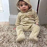 Yahia joined the competition — help win amazing prizes! toddler, child, baby, onesie, costume, bear_ears, carpet, floor, indoor, curious, sitting, plush, soft, cute, clothing, person, infant, young_child, cozy, warm