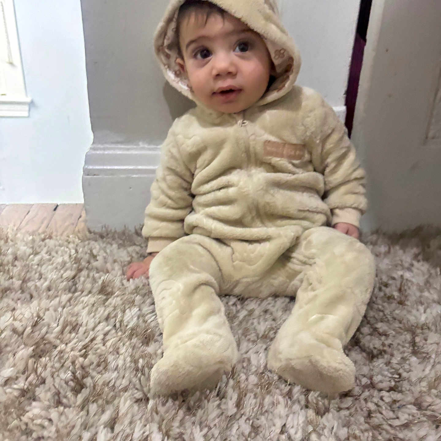 Yahia joined the competition — help win amazing prizes! baby, bear_ears, carpet, child, clothing, costume, cozy, curious, cute, floor, indoor, infant, onesie, person, plush, sitting, soft, toddler, warm, young_child