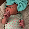 baby, newborn, infant, bow, headwear, onesie, patterned_clothing, blanket, soft, cute, small_hands, lying_down, indoor, portrait, child, apparel, curious, human, sleepwear, baby_girl