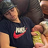 Ensley is registered to the contest to win money with this photo: baby, sleeping, young_person, hat, tshirt, nike_logo, armchair, indoor, window, light, comfort, resting, cradle, peaceful, casual_clothing, relaxation, family, infant, human, portrait