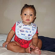 Eliyahu is registered to the contest to win money with this photo: baby, child, infant, sitting, red_clothing, bib, spiderman, bed, feet, toes, cute, portrait, indoor, person, young_child, looking_at_camera, expression, face, hands, skin