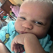 Ameliyah is registered to the contest to win money with this photo: baby, closeup, indoor, hand, face, infant, expression, resting, person, clothing, blue, skin, cute, young, portrait, head, eyes, furniture, background, cozy