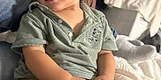 Alexander is registered to the contest to win money with this photo: bed, beige_pants, casual_clothing, child, cozy, cute, expression, face, hair, home, indoor, person, playful, polo_shirt, portrait, relaxing, sitting, smiling, toddler, young_child