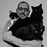 animal, black_and_white_cat, black_cat, casual_clothing, cat, cozy, facial_hair, feline, glasses, hugging, indoor, long_hair, man, monochrome, person, pet, photography, portrait, smile, watch