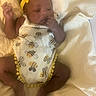 baby, infant, child, yellow_headband, bee_print, onesie, blanket, striped_blanket, sleeping, hand_near_mouth, cute, cozy, lying_down, skin, face, foot, relaxed, indoors, soft_lighting, newborn
