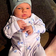 Mis is registered to the contest to win money with this photo: baby, blanket, bow_hat, couch, cozy, cute, feet, fingers, floral_pattern, hand, hat, indoor, infant, lying_down, newborn, onesie, portrait, skin, sleepy, soft_texture