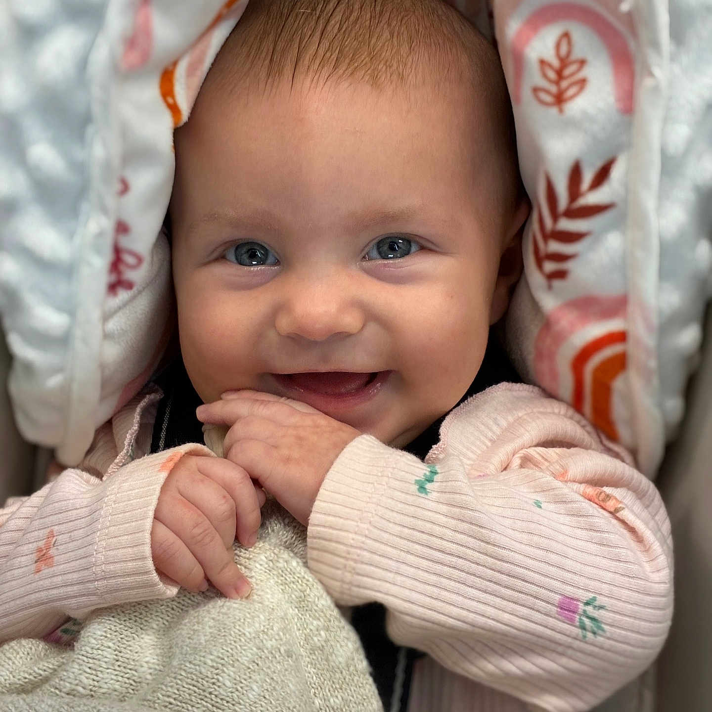 Aliza is registered to the contest to win money with this photo: adorable, baby, blanket, blue_eyes, child, close_up, cozy, cute, hands, happy, indoor, infant, knit_blanket, patterned_fabric, pink_clothing, portrait, sitting, smiling, soft_texture, warmth
