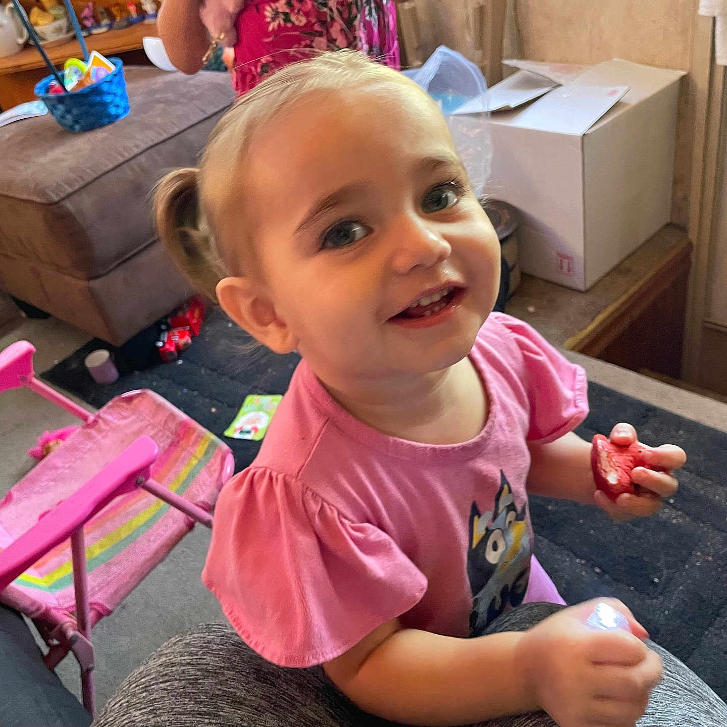 Charli joined the competition — help win amazing prizes! toddler, child, smiling, pink_shirt, pigtails, fruit, indoor, living_room, chair, box, carpet, toy, furniture, person, cute, happy, portrait, casual, playful, home