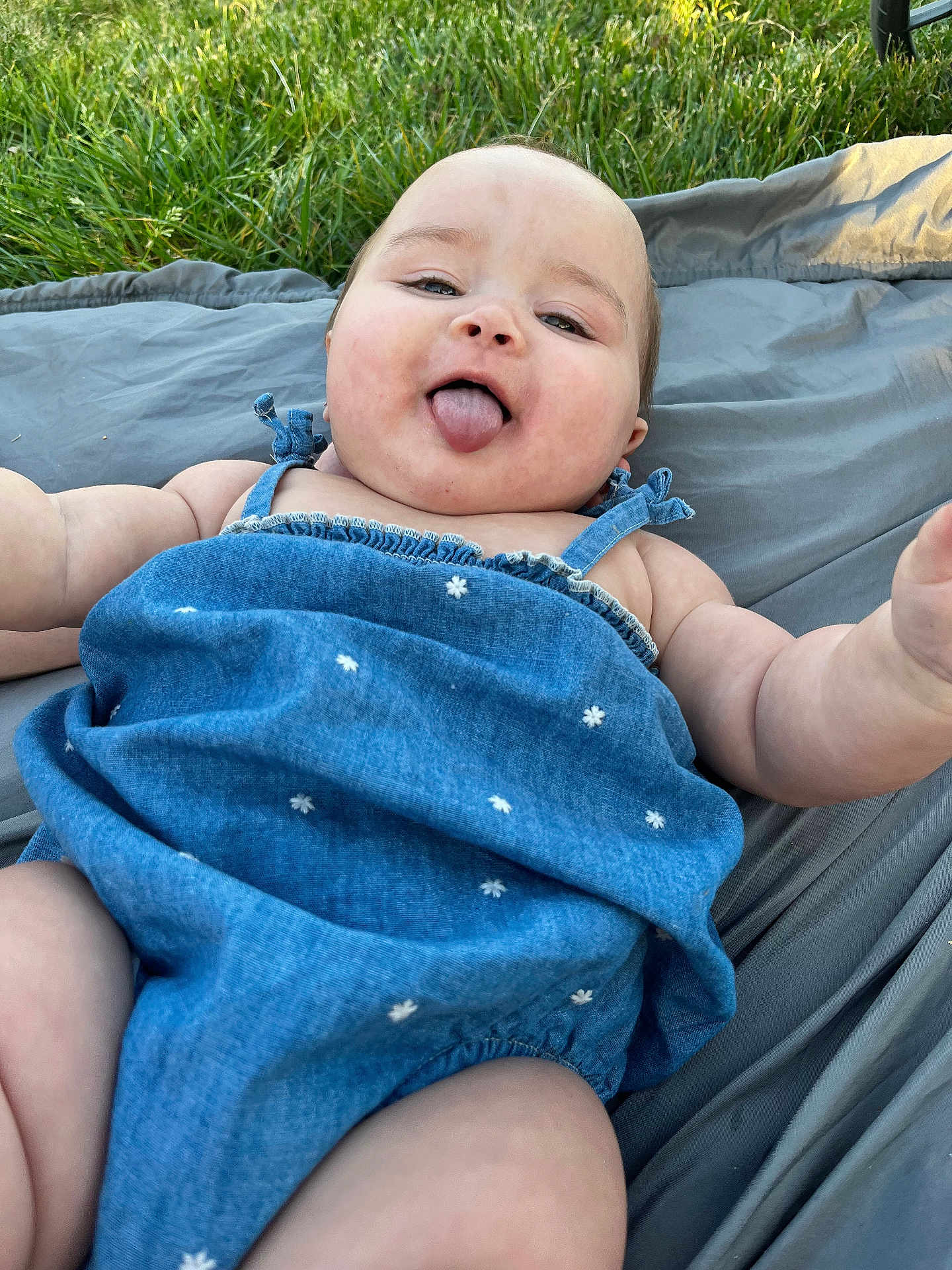 Eva joined the competition — help win amazing prizes! baby, infant, child, tongue_out, blue_dress, blanket, grass, outdoors, smiling, chubby_cheeks, portrait, candid, arm, leg, head, face, summer, picnic, fabric, playtime