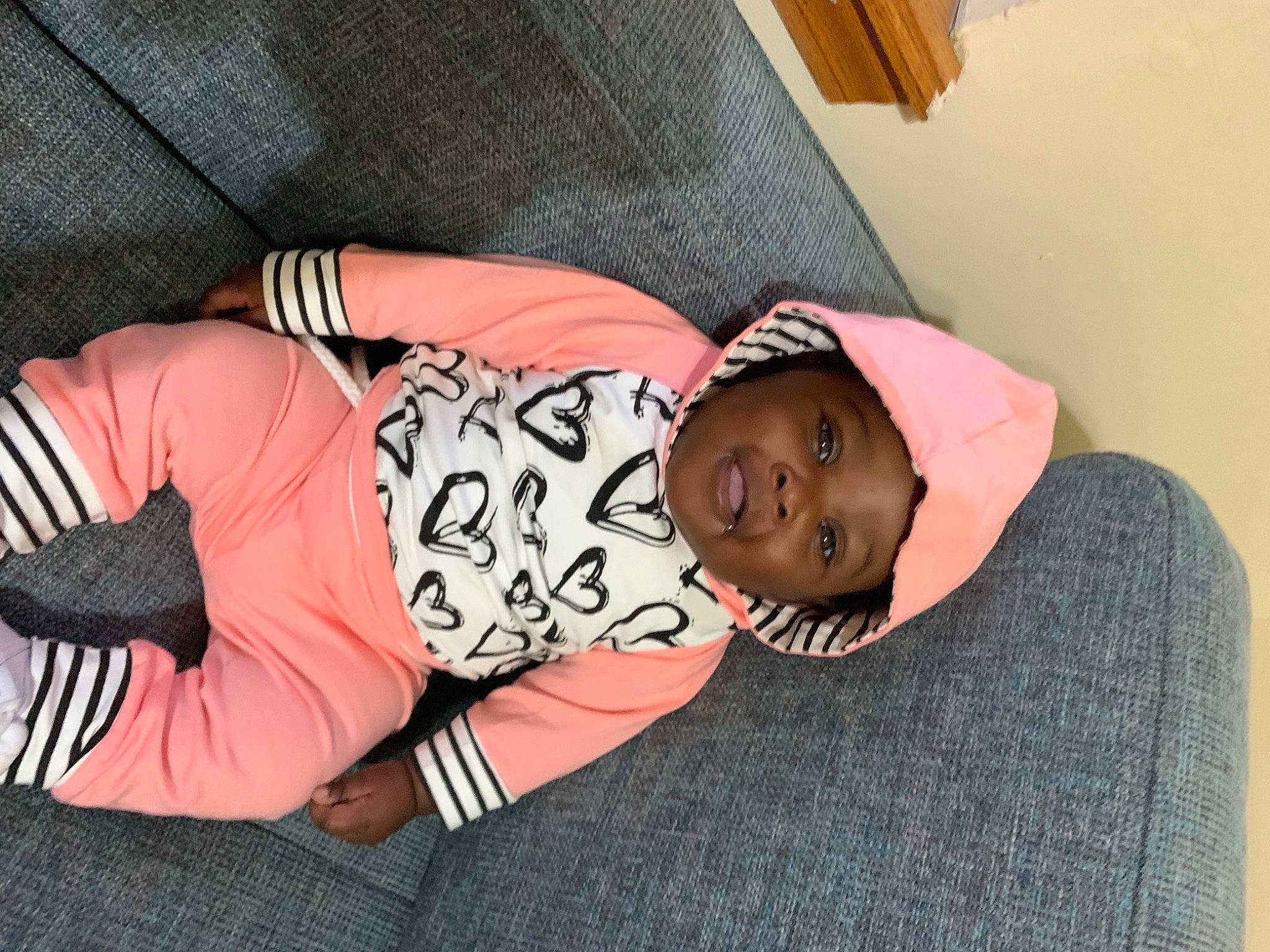 Ariya is registered to the contest to win money with this photo: arm, baby_toddler_clothing, comfort, elbow, hand, hat, headwear, human_body, human_leg, joint, knee, leg, linens, pattern, person, pink, sleeve, sunglasses, thigh, toddler