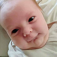 Katheryn is registered to the contest to win money with this photo: baby, infant, face, closeup, expression, skin, hair, white_clothing, lying_down, indoors, child, cute, soft_light, portrait, person, young, head, chubby_cheeks, casual, blanket