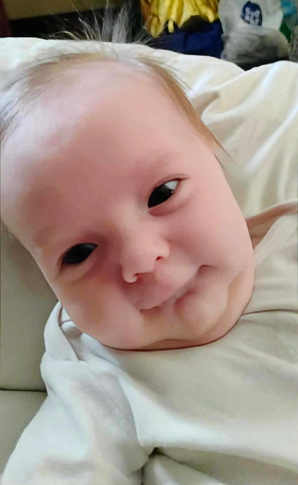 Katheryn is registered to the contest to win money with this photo: baby, infant, face, closeup, expression, skin, hair, white_clothing, lying_down, indoors, child, cute, soft_light, portrait, person, young, head, chubby_cheeks, casual, blanket