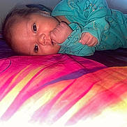 Taoahere participe au concours pour gagner de l'argent avec cette photo : baby, bed, blanket, child, clothing, colorful, cute, dinosaur_pattern, expression, face, hand, head, indoors, infant, lying_down, onesie, portrait, skin, sleepwear, young