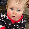 baby, child, infant, portrait, sitting, outdoor, bench, wood, leaf, blue_eyes, blond_hair, rosy_cheeks, black_outfit, patterned_clothing, red_trim, looking_at_camera, close_up, face, natural_light, autumn
