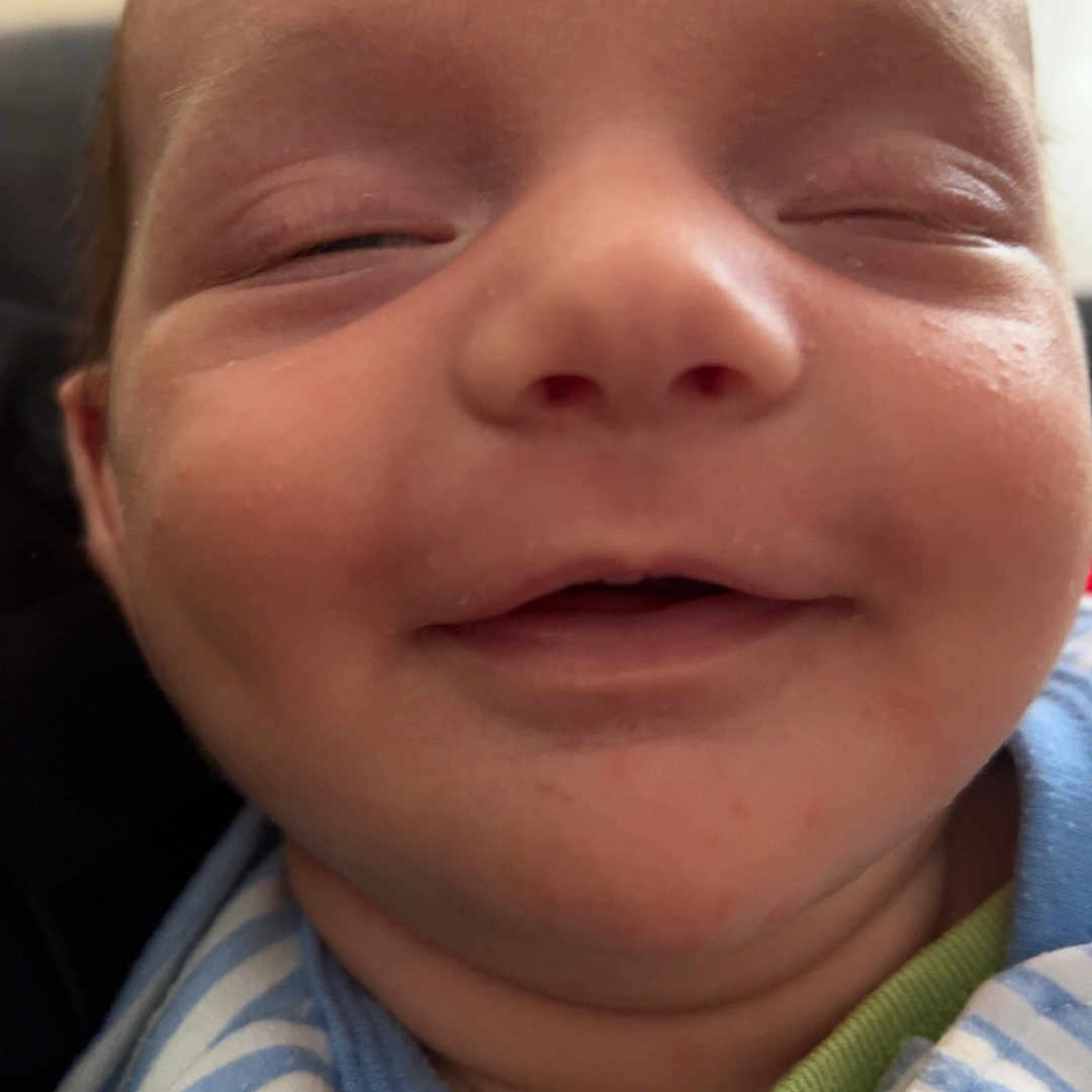 Mason is registered to the contest to win money with this photo: baby, blue, child, close_up, cute, face, green, happy, head, indoors, infant, newborn, peaceful, person, portrait, sleepy, smile, soft_skin, striped_clothing, young_child