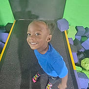 Syere is registered to the contest to win money with this photo: child, smiling, trampoline, foam_blocks, blue_shirt, braided_hair, socks, play, indoor, happy, person, colorful, fun, active, young, feet, floor, background, recreation, casual