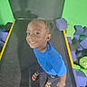 child, smiling, trampoline, foam_blocks, blue_shirt, braided_hair, socks, play, indoor, happy, person, colorful, fun, active, young, feet, floor, background, recreation, casual