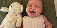 Emilio participe au concours pour gagner de l'argent avec cette photo : baby, smiling, teddy_bear, blanket, infant, cute, child, happy, soft_toy, lying_down, indoors, clothing, small_hands, face, expression, comfort, relaxation, warm_colors, person, portrait