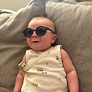 Emilio participe au concours pour gagner de l'argent avec cette photo : baby, sunglasses, onesie, couch, infant, smiling, indoor, child, cute, relaxed, clothing, seat, young, person, fabric, portrait, comfortable, cozy, casual, home